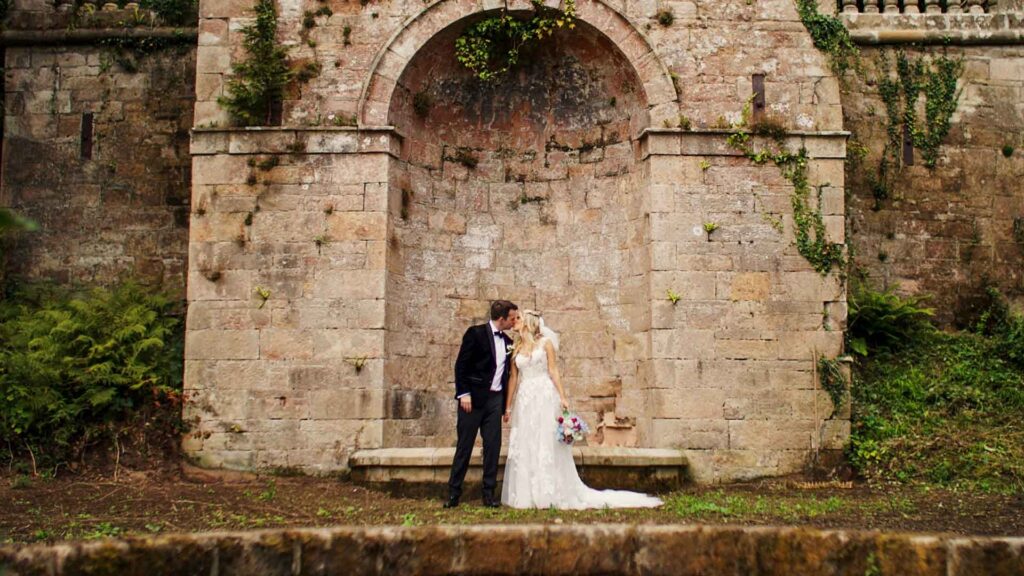 Sarah & James sharing a kiss at rustic traditional garden's of Drenagh Estate